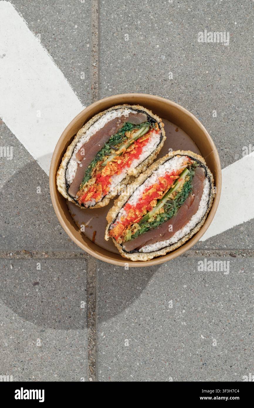 Sushi-Burger vor dem Hintergrund eines Schildes mit der Aufschrift "Fußgängerzone" Stockfoto