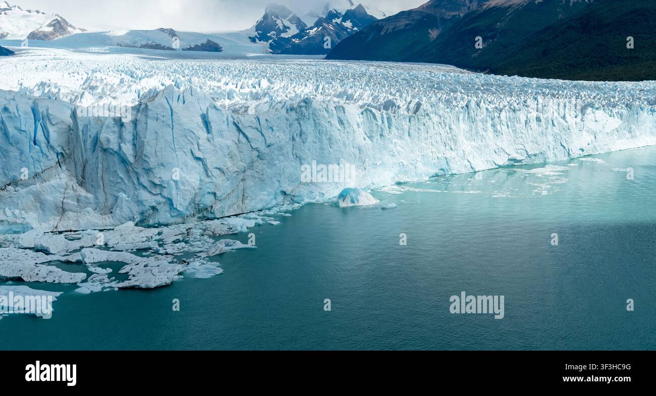 Dramatischer Blick auf den blauen Gletscher, der in kaltes Seewasser unter dem Himmel fließt Stockfoto