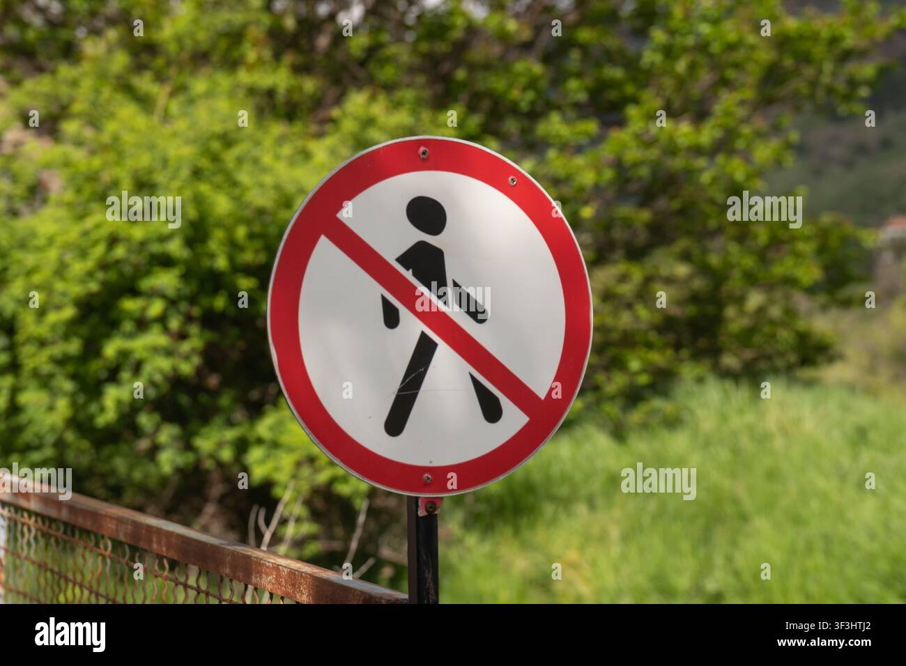 Rundes Verkehrsschild mit rotem Rand und diagonaler Linie über einem schwarzen Fußgänger-Symbol, das einen gesperrten oder unsicheren Gehbereich anzeigt Stockfoto