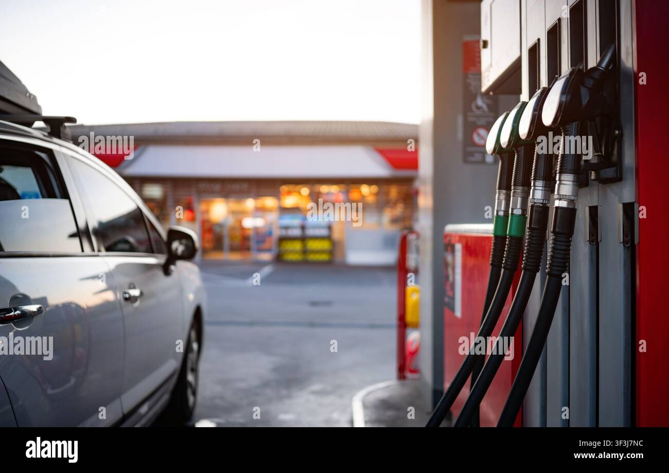 Auto, das an der Zapfsäule einer Tankstelle geparkt ist, mit Benzin- und Diesel-Spritzen in der Nähe hängend Stockfoto