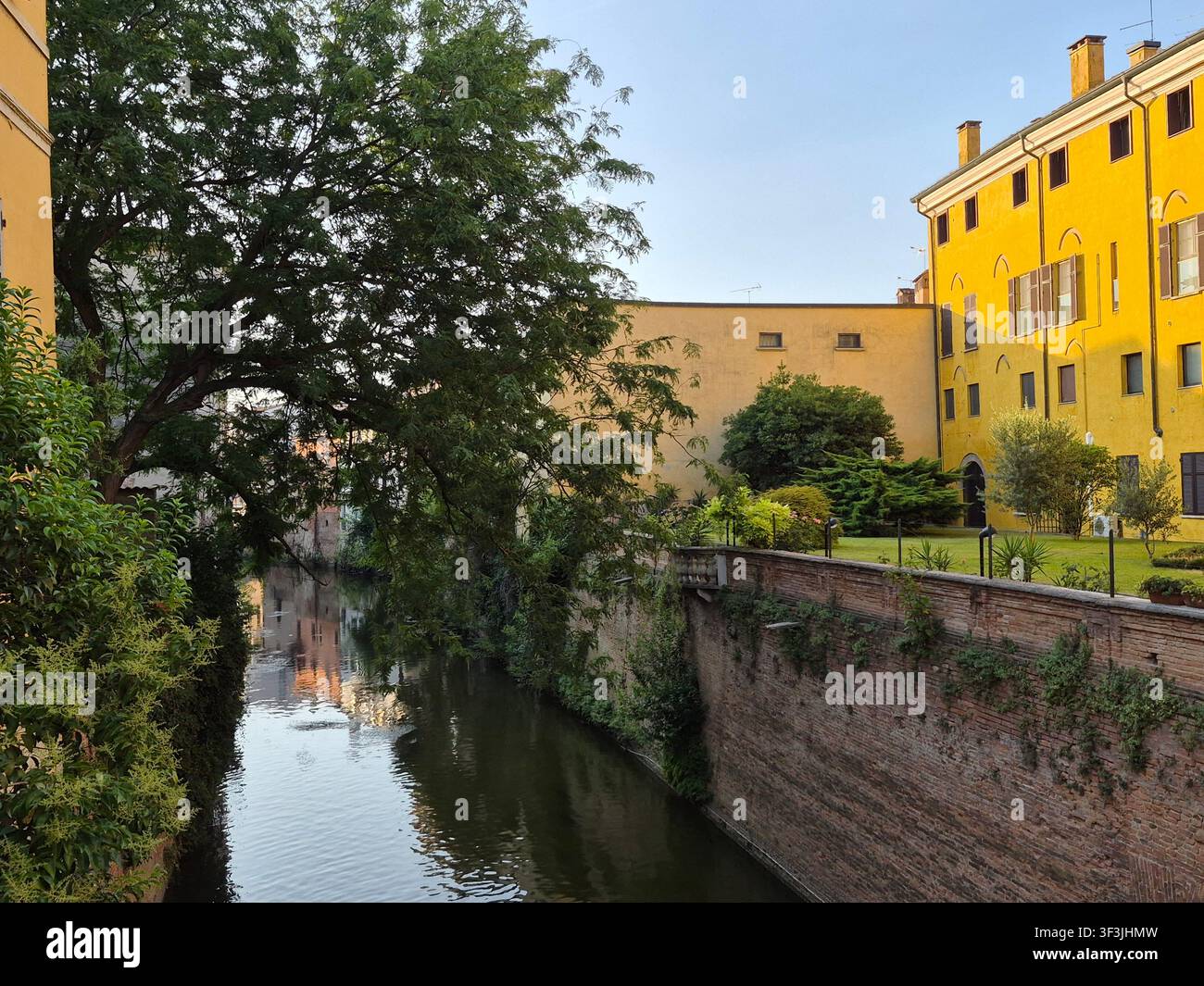 Sehenswerter Blick auf den historischen Rio-Kanal, umgeben von alten Gebäuden und üppigen grünen Bäumen in Mantua, Lombardei, Italien - Smartphone-aufgenommenes Stockfoto
