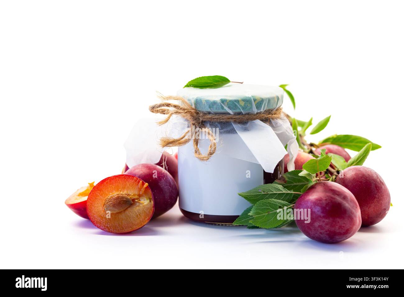 Hausgemachte Pflaumensauce in einem Glas mit reifen Früchten auf weißem Hintergrund. Stockfoto