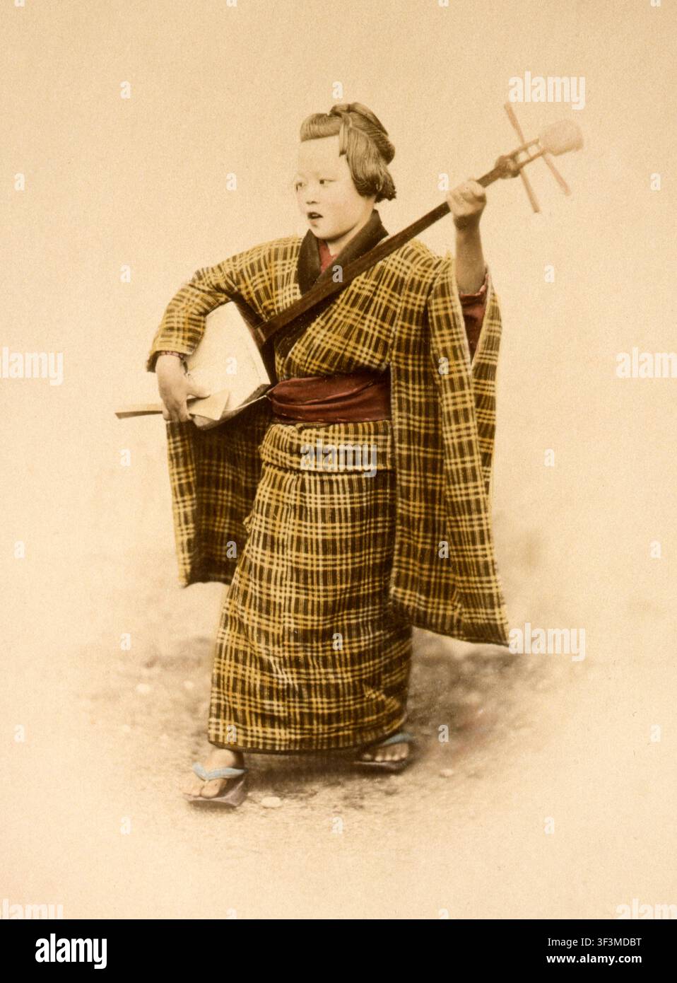 Straßenmusikerin – junge Frau, die eine Shamisen spielt, Detail aus einem Foto von Felice Beato, das drei Straßenmusiker zeigt – ca. 1877 Stockfoto