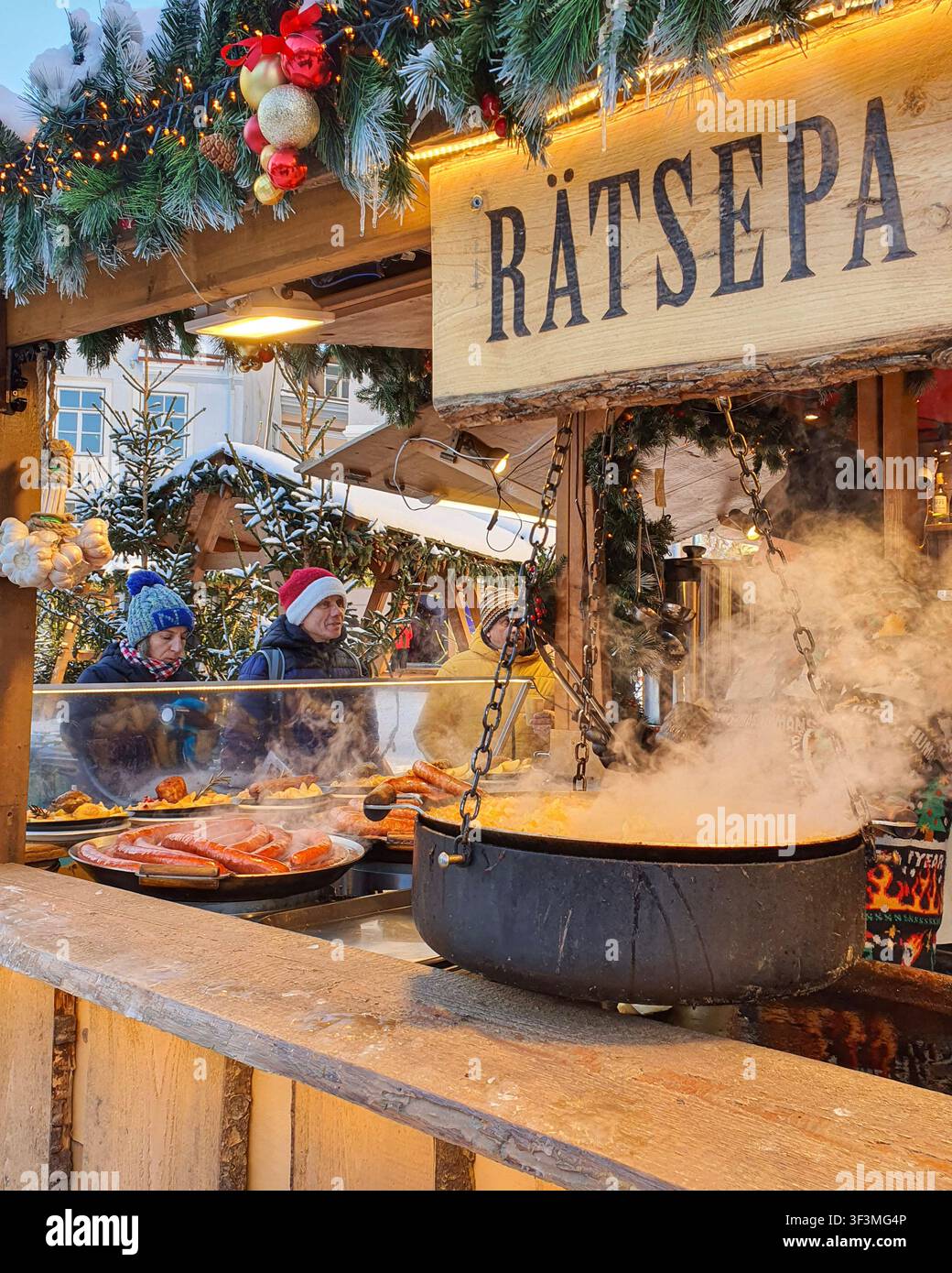 Tallinn, Estland - 7. Jan. 2024: Händler kochen Würste in einem großen Topf an einem Weihnachtsmarkt-Stand. Stockfoto
