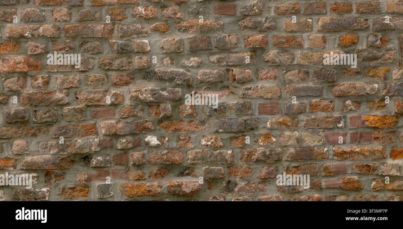 Eine detaillierte Textur einer alten roten Ziegelmauer mit unregelmäßiger Platzierung und dicken, verwitterten Mörtelstellen. Stockfoto