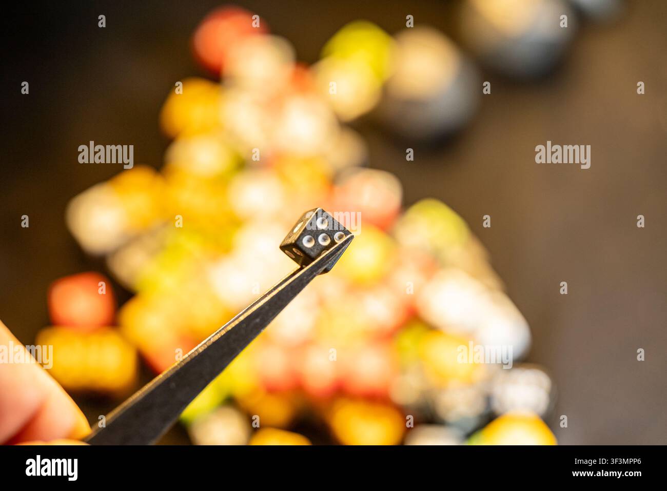 Makrofotografie des Auswählens eines einzelnen Miniatur-Spielsteins aus einem chaotischen Haufen Stockfoto