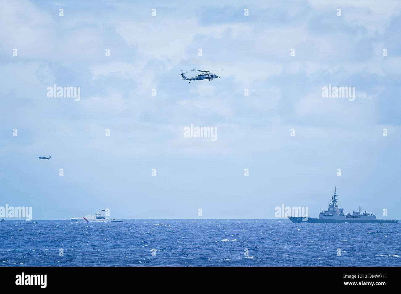 HMAS Sydney, ein Zerstörer der Klasse Hobart der Königlichen Australischen Marine, und BRP Gabriela Silang, ein Hochseepatrouillenboot der Klasse Gabriela Silang der Philippinischen Küstenwache, nehmen an der Gruppenregatta Rim of the Pacific 2026 teil, wobei zwei MH-60-Hubschrauber über ihnen fliegen, im Rahmen einer multinationalen Übung mit 30 Nationen und über 30.000 Teilnehmern. Stockfoto