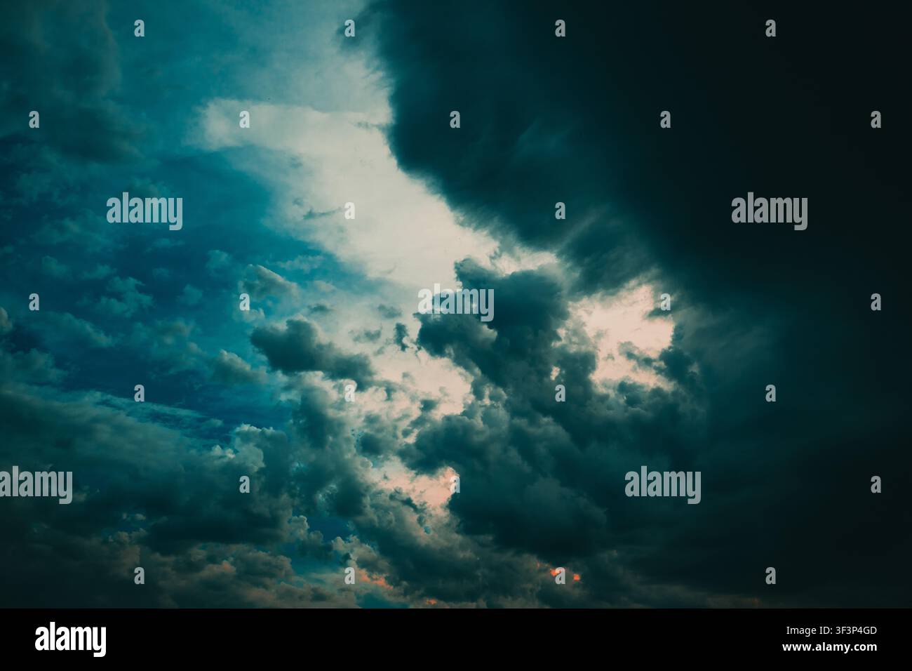Stimmungsvolle, dramatische Sturmwolken fegen über einen turbulenten Abendhimmel und erzeugen starken Kontrast und ein Gefühl bevorstehenden Wetters. Dunkle, strukturierte Wolken an Stockfoto