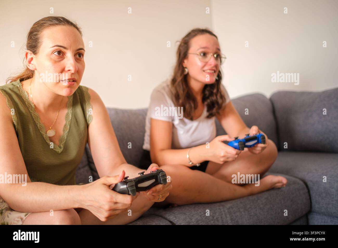 Junge Frauen sitzen auf einem Sofa und spielen mit Videospiel-Controllern Stockfoto