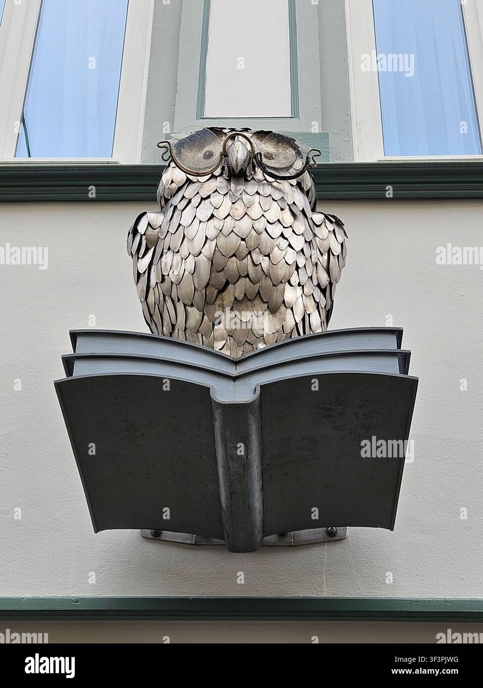 Handgefertigte kleine Eulen-Skulptur auf offenem Buch an der Buchladenfassade, Lachsgasse nahe Anger, Erfurt, Deutschland - Smartphone-aufgenommenes Stockfoto