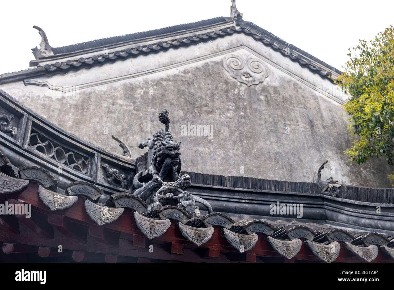 Ein Dachschmuck erhebt sich über Ziegeldachrinnen und eine Putzwand im Jade-Buddha-Tempel in Shanghai, China, an einem Frühlingstag Stockfoto