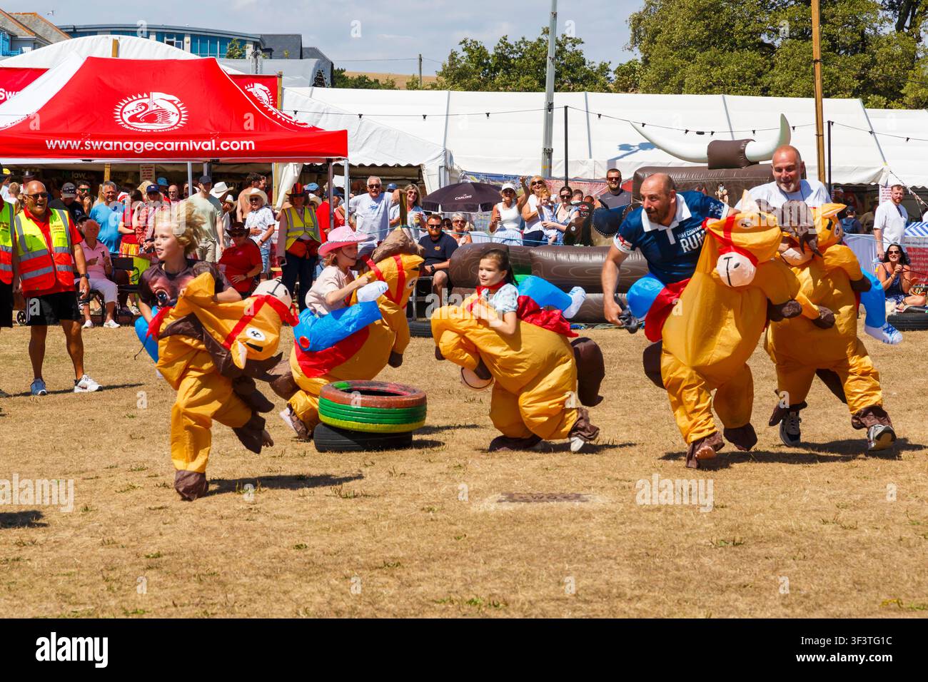 Swanage, Dorset UK. 25. Juli 2026. Das Swanage-Karnevall beginnt mit dem Thema "Ein verrückter Western im Carnival Canyon" mit Aktivitäten und Veranstaltungen in der kommenden Woche. Tausende strömen an einem heißen sonnigen Tag nach Swanage zum Karneval. Die heutigen Veranstaltungen umfassen Rodeo Stampede. Die Teilnehmer haben Spaß beim Rodeo Stampede. Credit: Carolyn Jenkins/Alamy Live News Stockfoto
