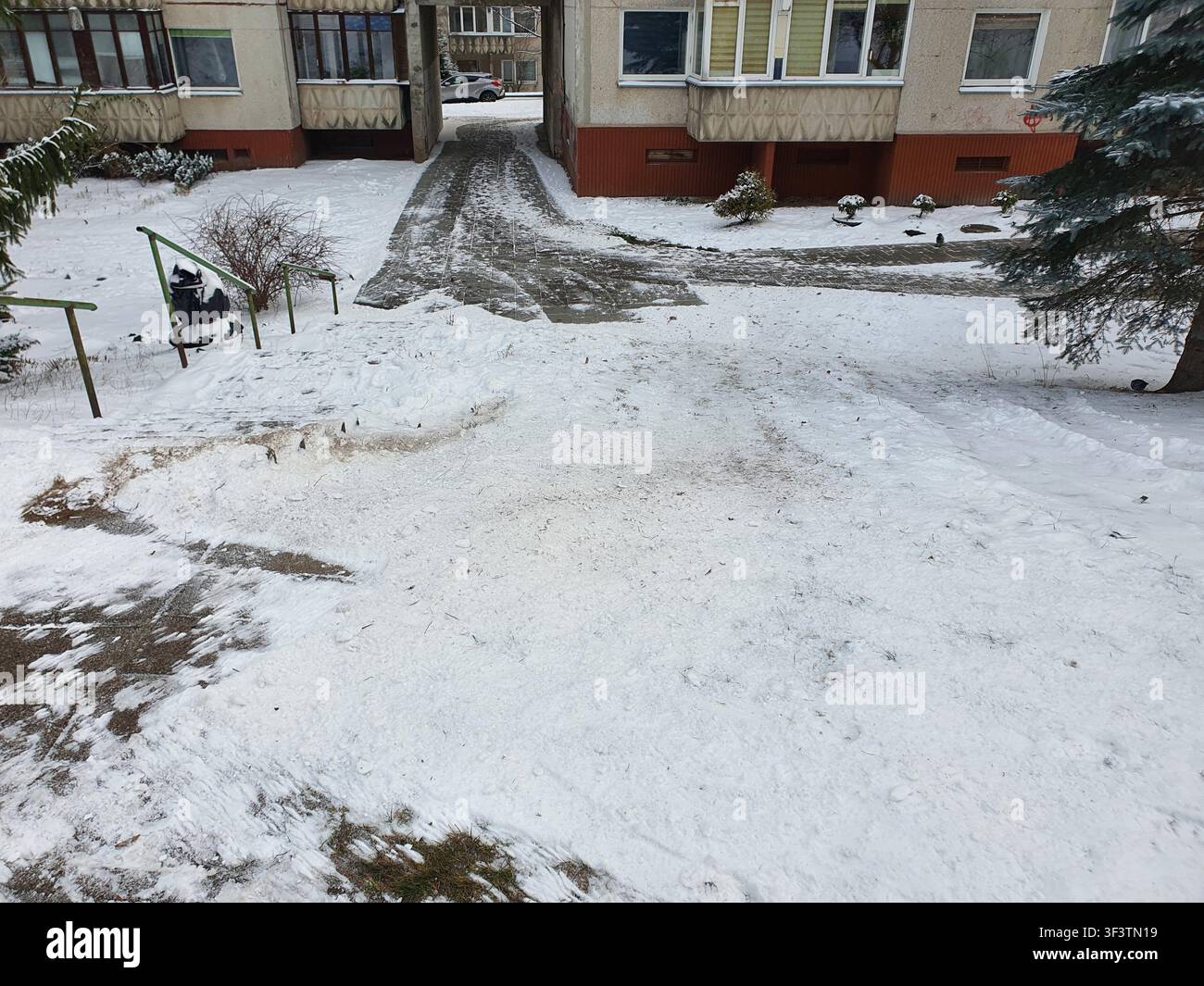 Eine Winterszene, die einen schneebedeckten Wohnhof zwischen mehrstöckigen Wohnhäusern mit Architektur aus der Sowjetära zeigt. Die Gebäude Stockfoto