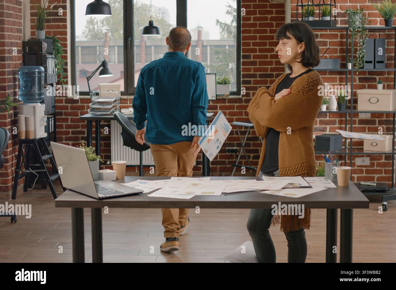 Wütender Büroangestellter wirft Diagrammpapiere nach einem Streit, zeigt Arbeitsplatzstress, Finanzdokumente und Geschäftsfrustration. Stockfoto