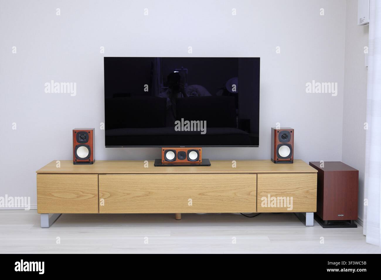 Großer Fernseher und Heimkinosystem auf einem hölzernen TV-Ständer Stockfoto