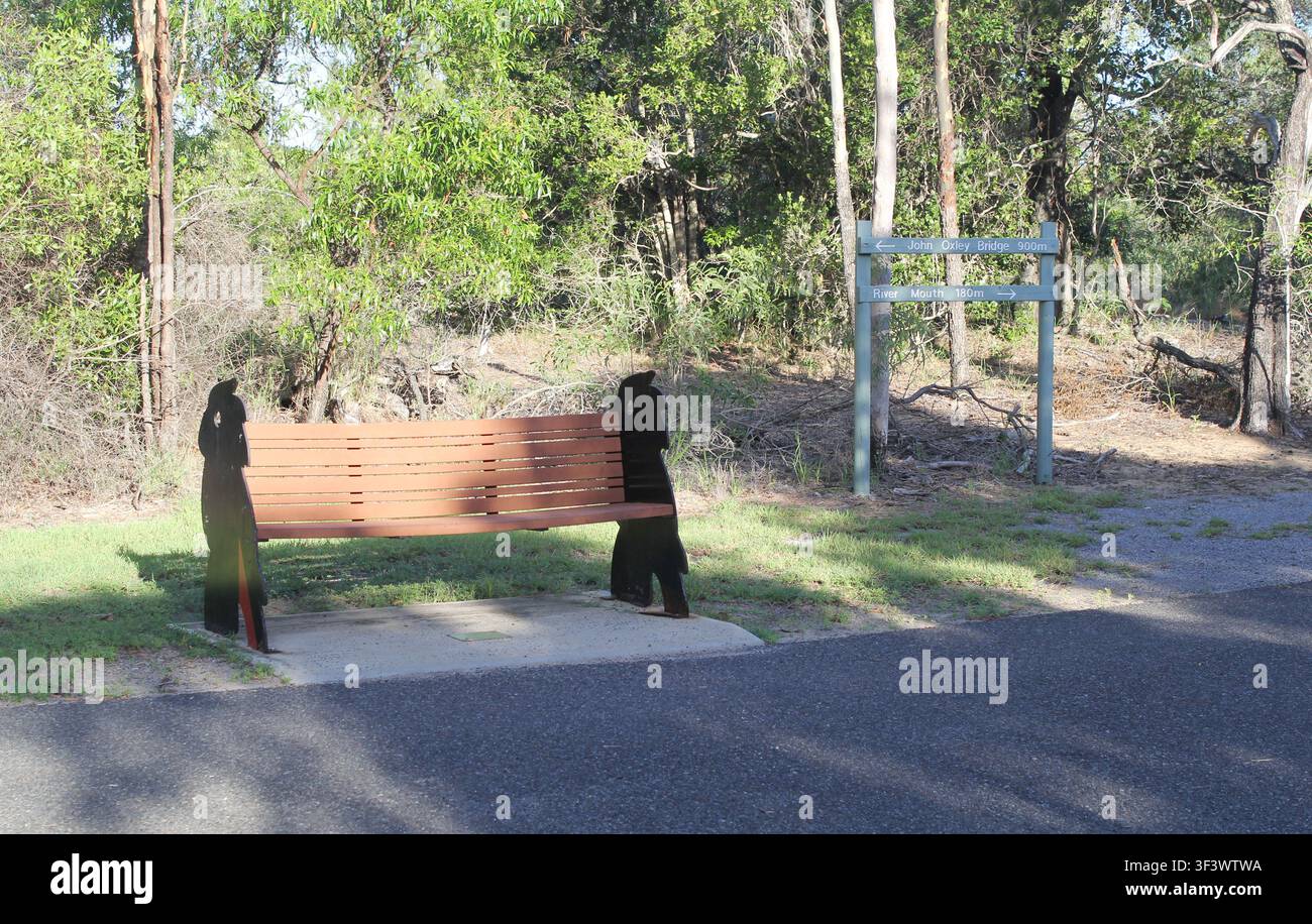 Eine Parkbank mit dekorativen schwarzen Kakadu-Silhouetten entlang eines Wanderwegs im Canoe Point Reserve in Tannum Sands, Queensland, Australien Stockfoto