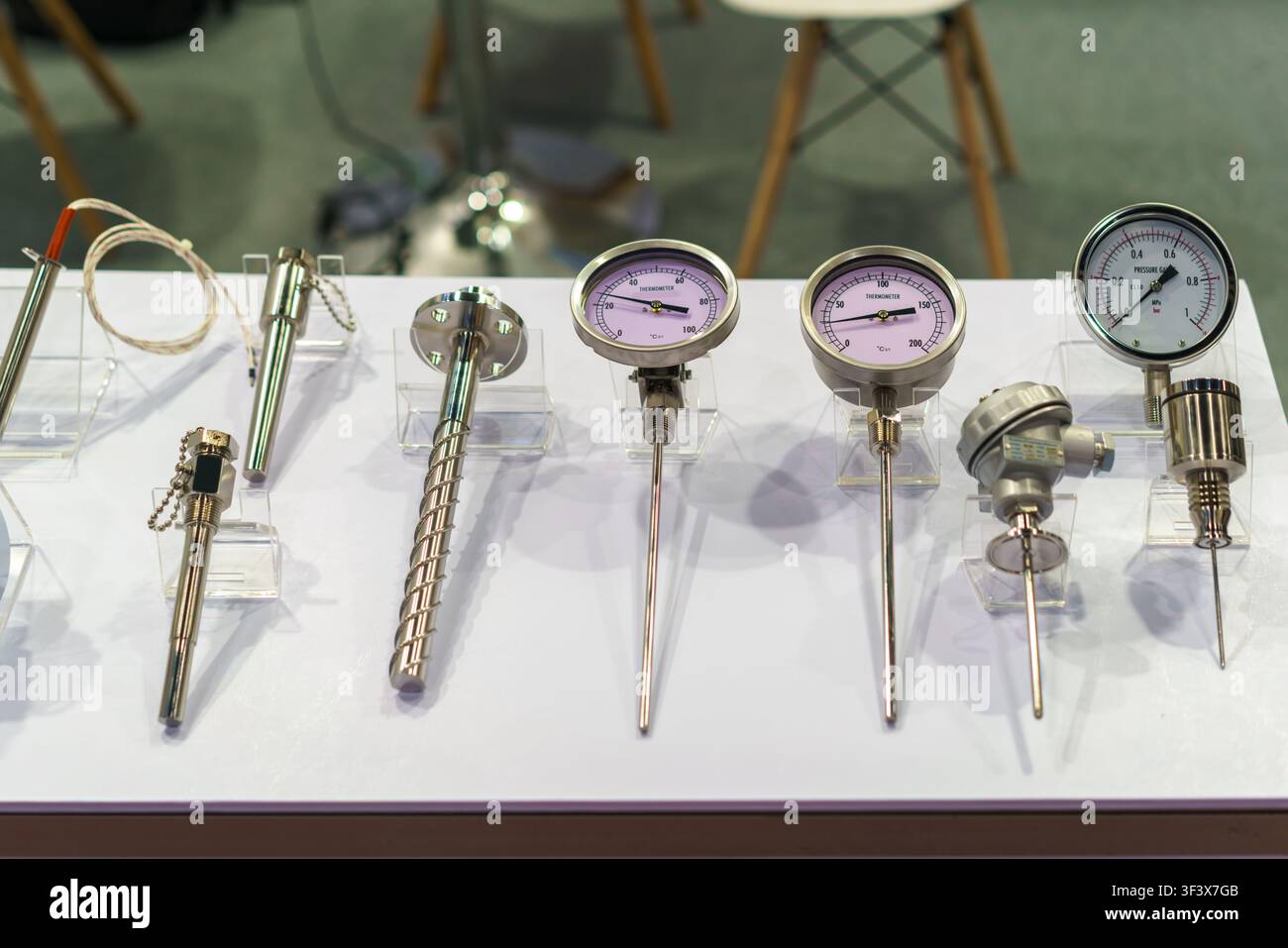 Nahaufnahme verschiedener industrieller Bimetall-Thermometer, Druckmessgeräte und Temperatursensoren, die auf klaren Acrylständern auf einer Ausstellung arrangiert sind Stockfoto