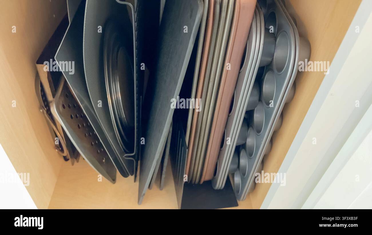 Vertikaler Stapel von Backblechen und Pfannen im Schrank Stockfoto