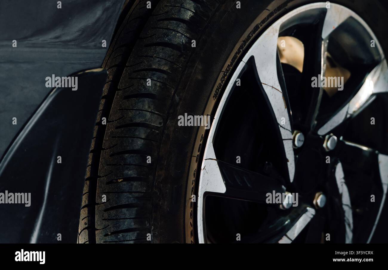 Nahaufnahme eines Autoreifprofils und einer zweifarbenen Aluminiumfelge an einem Fahrzeug. Stockfoto