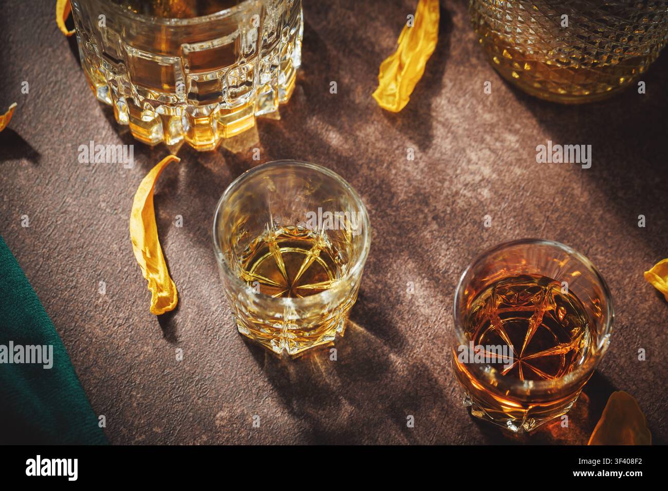 Oberansicht der Whiskeyverkostungsausstattung mit Kristallgläsern, bernsteinfarbenem Likör, eleganten Reflexionen und gelben Tulpenblüten für Premium-Restaurant- und Bar-Menüdesign Stockfoto