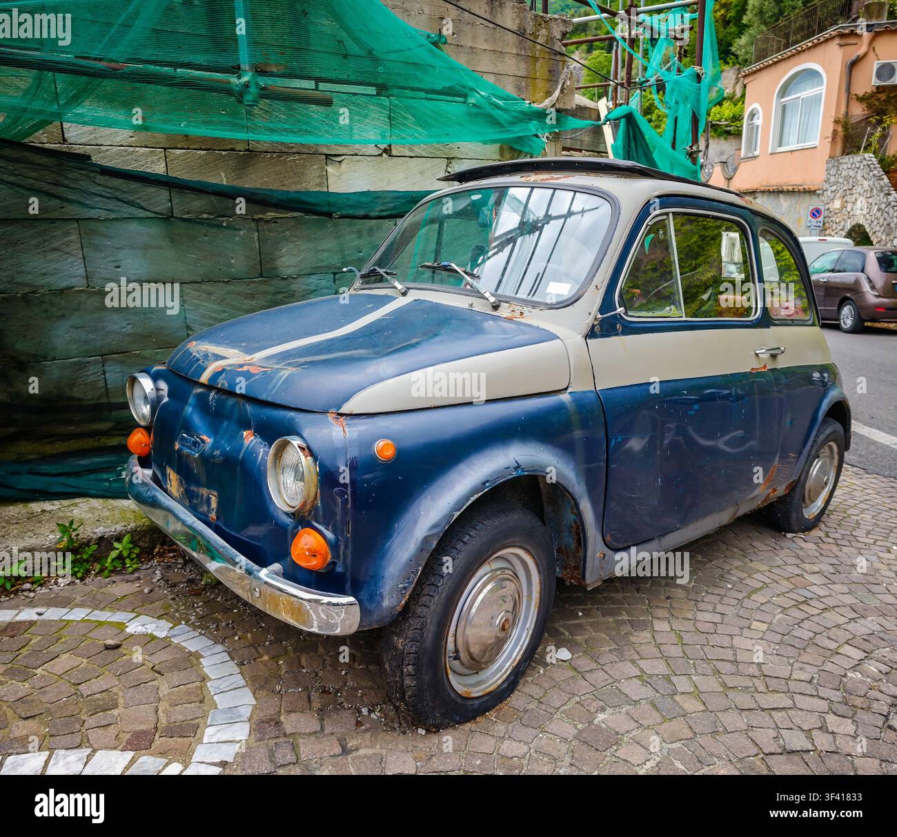 Kleines verlassenes italienisches Auto am Straßenrand in den steilen Straßen von Positano, Italien, das den authentischen Charme und den einzigartigen Charakter der Stockfoto