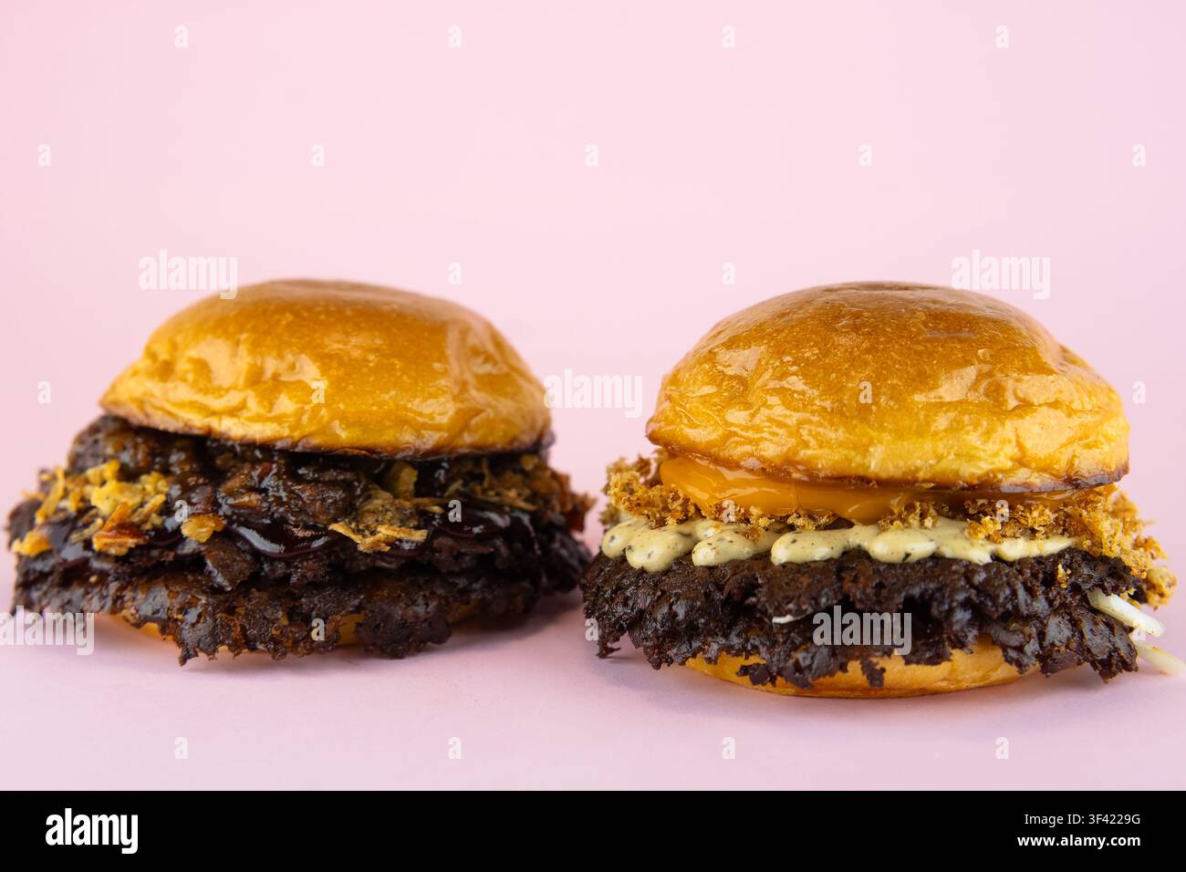 Zwei Gourmet-Smash-Burger auf schlichtem rosa Hintergrund Stockfoto
