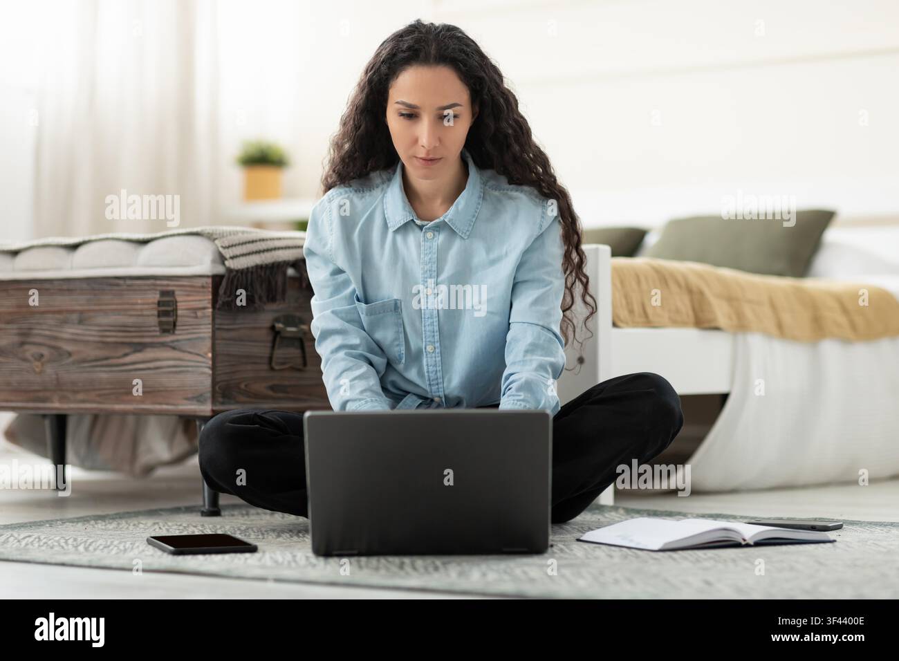 Konzentrierte junge lateinamerikanische Frau arbeitet an einem Laptop in einer gemütlichen Heimumgebung, Gewichtsabnahme-Konzept Stockfoto