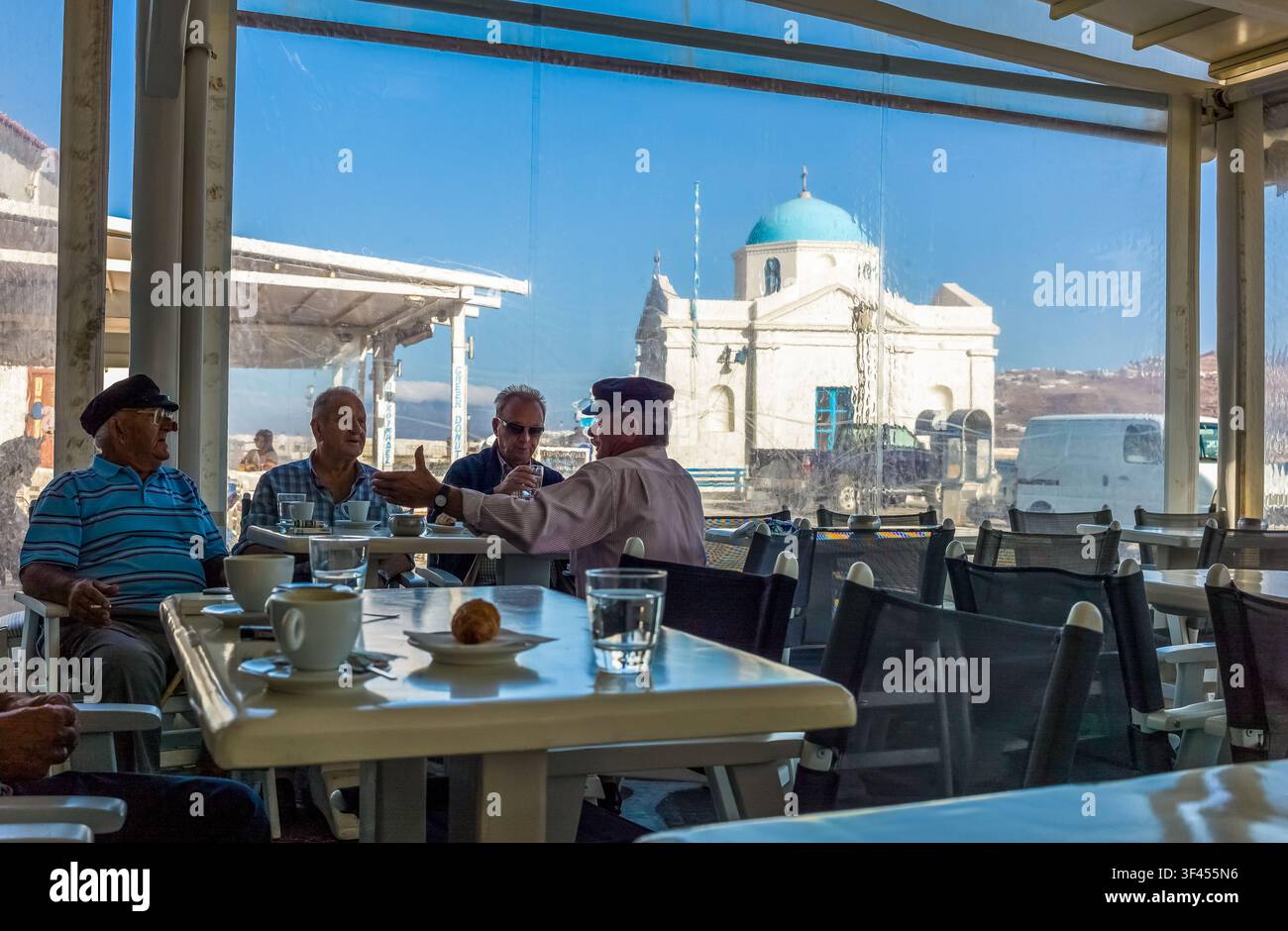 Griechenland, Mykonos: Chora, einheimische ältere Menschen unterhalten sich in einer Bar des Hafens Stockfoto