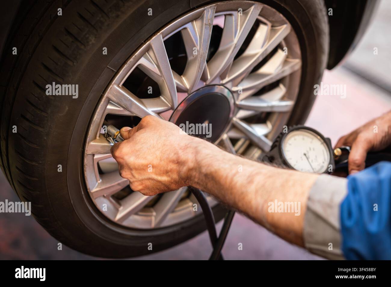 Mechanics Hände überprüfen den Reifendruck des Autos für Fahrzeugsicherheit und Leistung Stockfoto