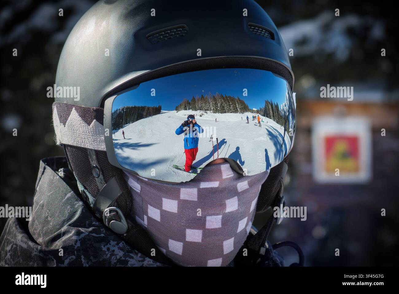 Ein Skifahrer mit Helm und verspiegelter Skibrille auf einer Skipiste. *** Ein Skifahrer trägt einen Helm und verspiegelte Skibrillen auf einer Skipiste Stockfoto