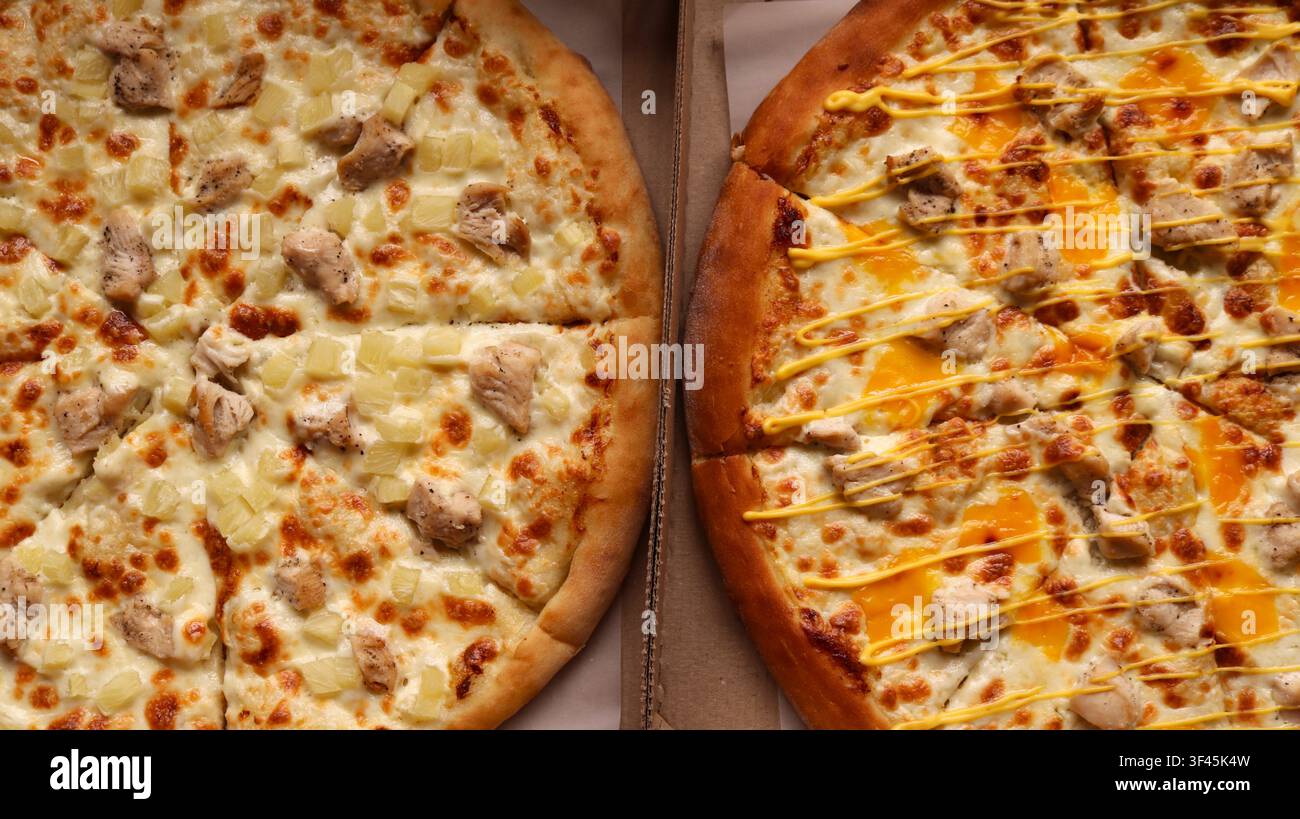 Zwei köstliche runde Pizzen in Schachteln. Links ist ein Hühnerfilet, saftige Ananas und Mozzarella. Rechts ist ein Hühnerfilet Stockfoto