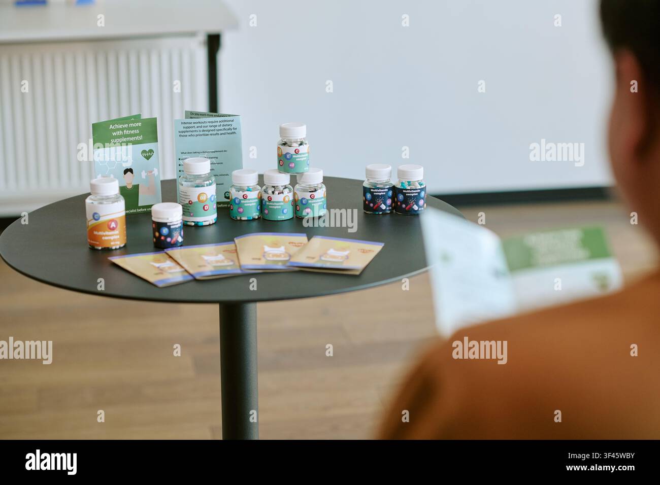 Junger erwachsener Mann, der ein Nahrungsergänzungsmittel-Display während einer Geschäftsschulung überprüft Stockfoto