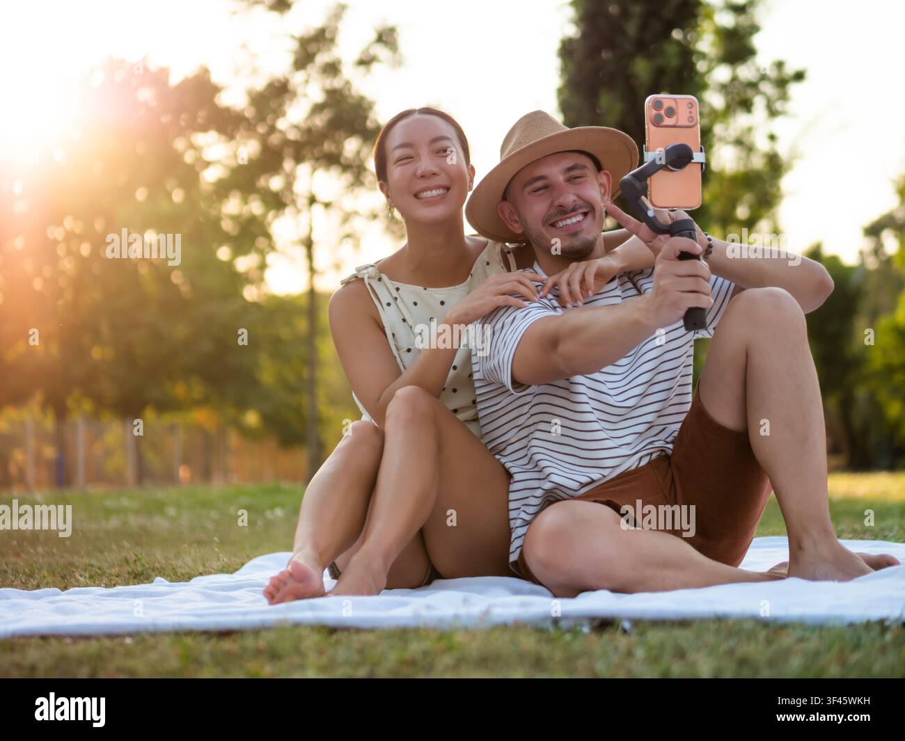 Ein fröhliches Paar teilt einen verspielten Moment, während es sich in einem malerischen Park aufnimmt. Stockfoto