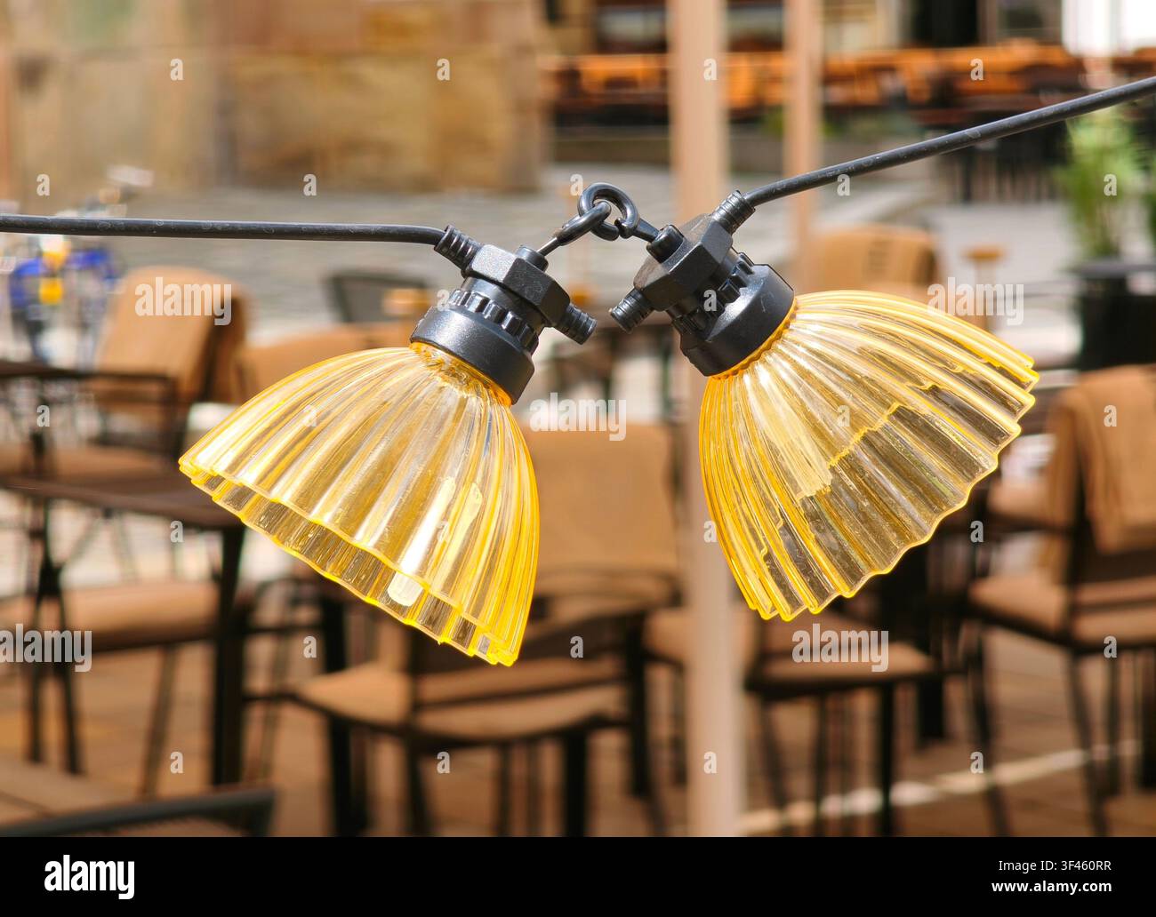 Dekorative gelbe Lichterketten, die an einer leeren Außenterrasse eines Restaurants hängen Stockfoto