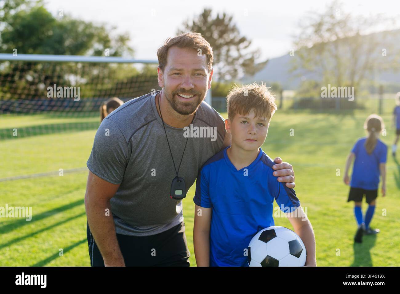 Kind-Fußballspieler mit seinem Trainer. Stockfoto
