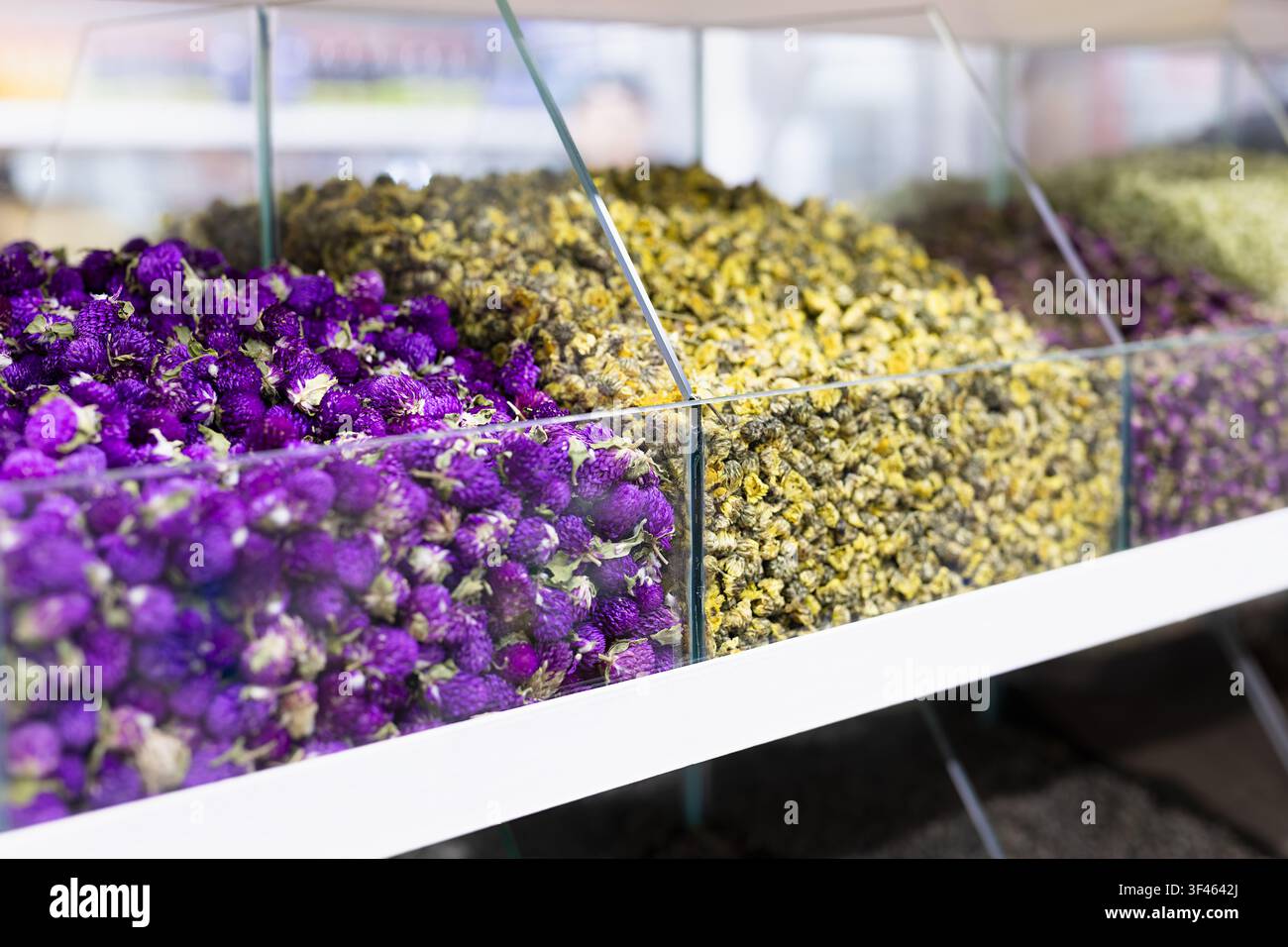 Getrocknete Blumen und Kräutertee in Gläsern auf einem orientalischen Basar in Bukhara. Bunte violette und gelbe Blüten schaffen eine lebhafte Marktszene Stockfoto