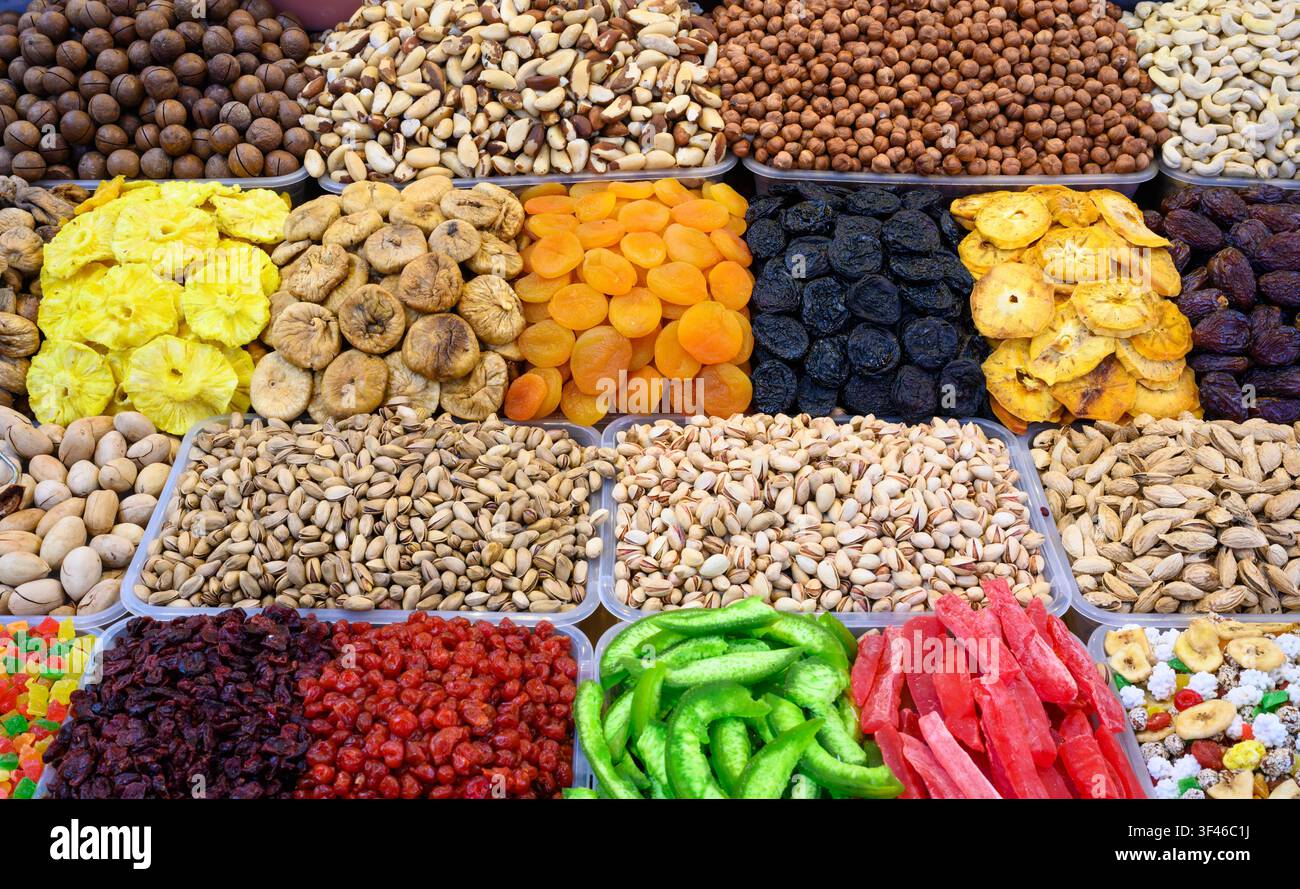 Eine lebendige und reichhaltige Marktauslage mit einer großen Vielfalt an Nüssen und Trockenfrüchten, die in klaren Plastikbehältern angeordnet sind. Die Draufsicht zeigt Stockfoto