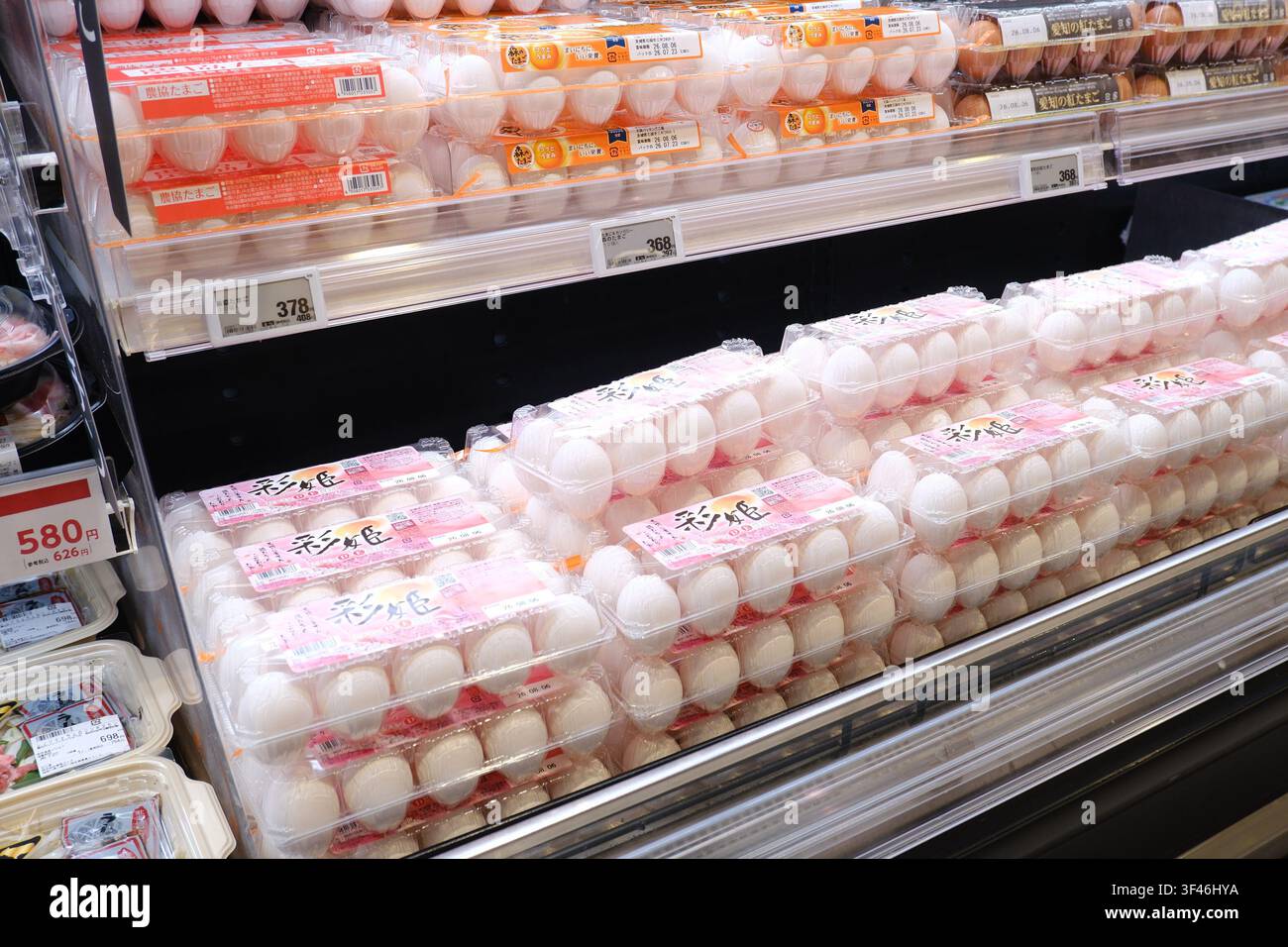 Kartons mit frischen weißen Eiern, gestapelt auf gekühlten Regalböden in einem japanischen Supermarkt. Stockfoto