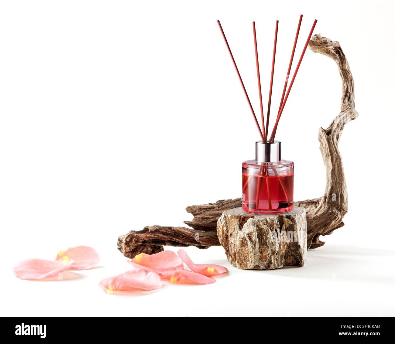 Rosenessenz-Roomspray-Flasche auf einem Steinständer neben Treibholz und Rosenblättern isoliert auf weißem Hintergrund. Stockfoto