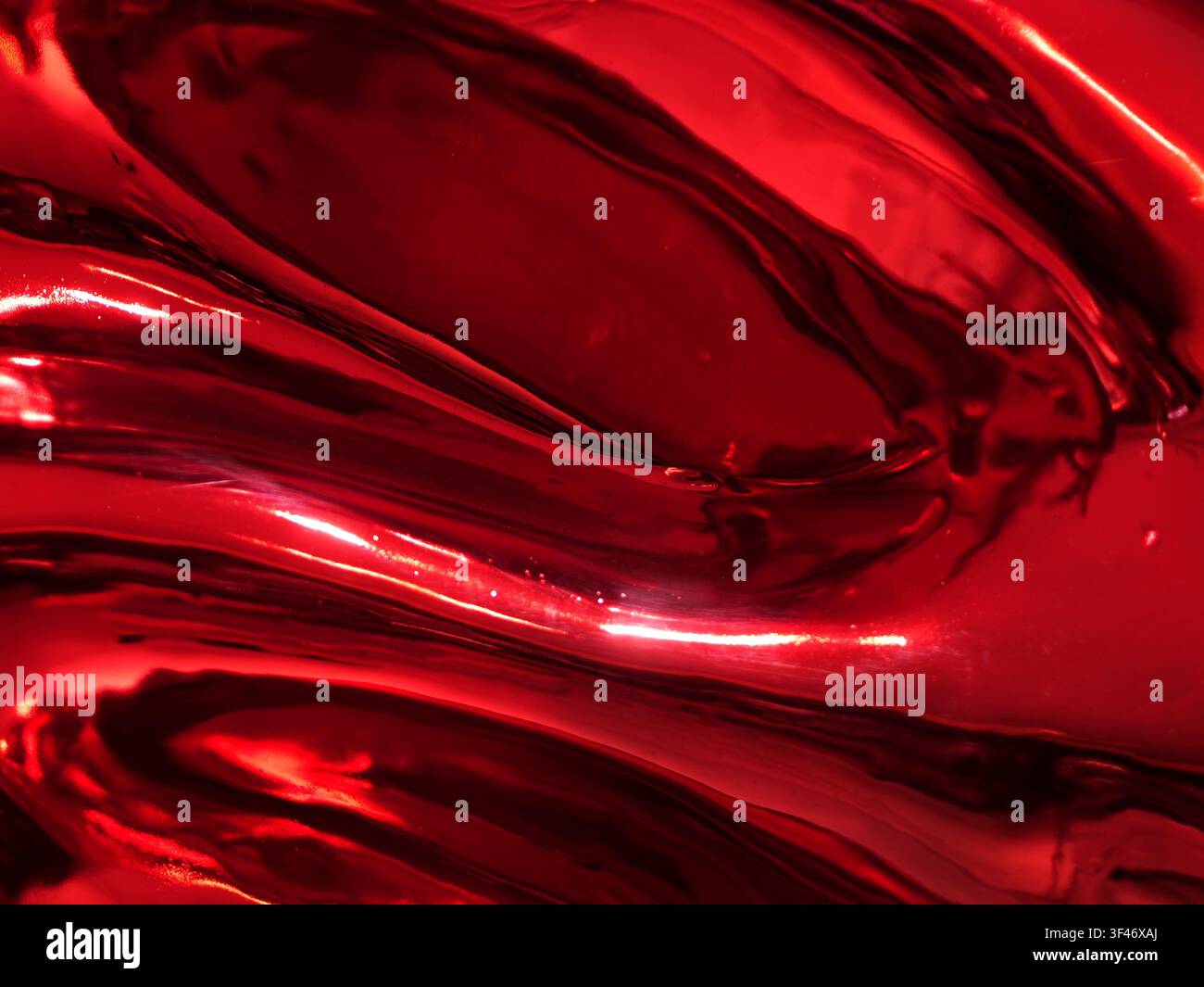 Nahaufnahme einer glänzenden, reflektierenden roten Metalloberfläche mit glatten flüssigen Wellen, hellen Reflexen und tiefen Schatten, die eine abstrakte, dynamische Textur erzeugen Stockfoto