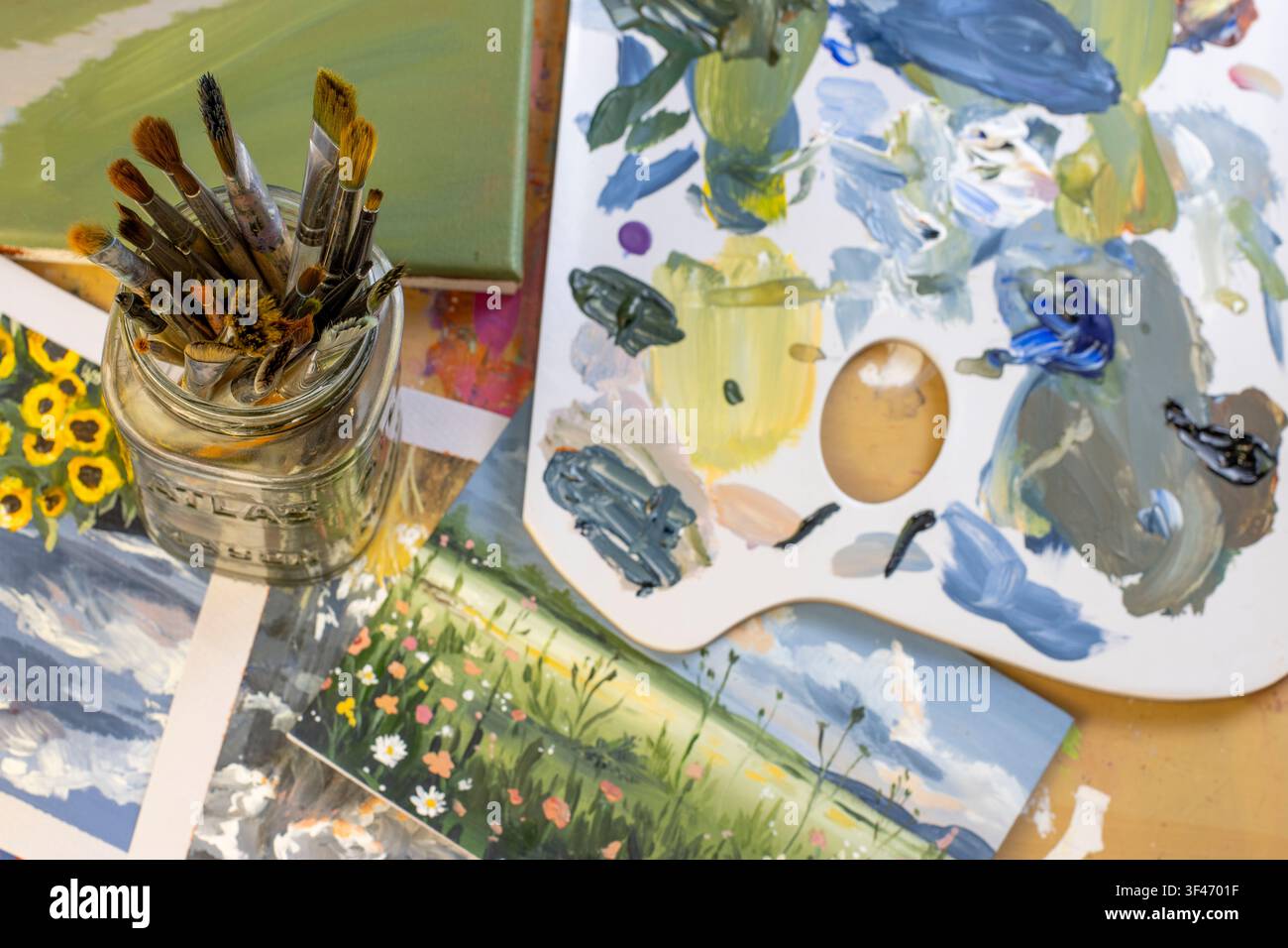 Künstlermalkolben mit Pinseln und Palette, Top-Down-Flachlage, kreativer Arbeitsbereich Stockfoto