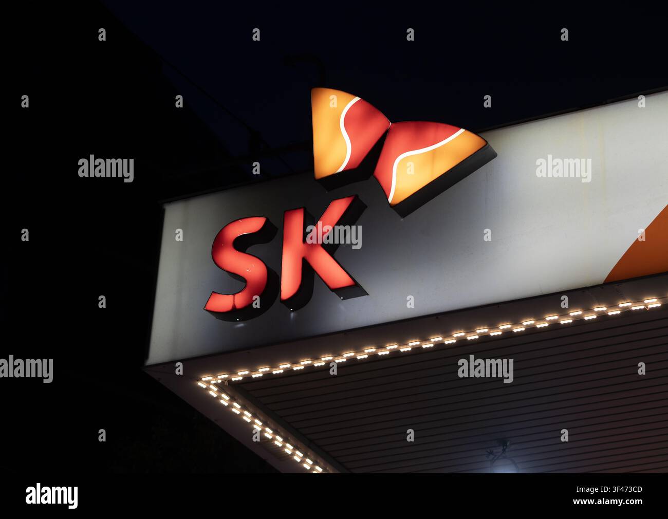SK-Korporationsmarkenlogo-Schild und Firmenidentitätsanzeige bei Nacht mit warmem Licht und einem sauberen dunklen Hintergrund, Nahaufnahme eines beleuchteten SK l Stockfoto