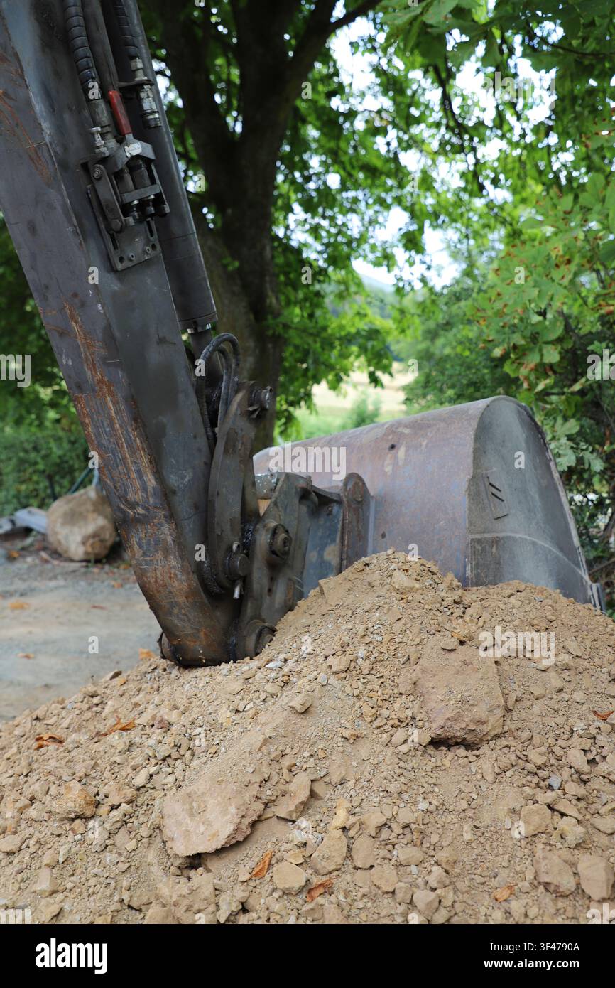 Nahaufnahme des Baggerschaufels und des Anbauteils, die an einer Baustelle im Freien in den Boden graben. Stockfoto