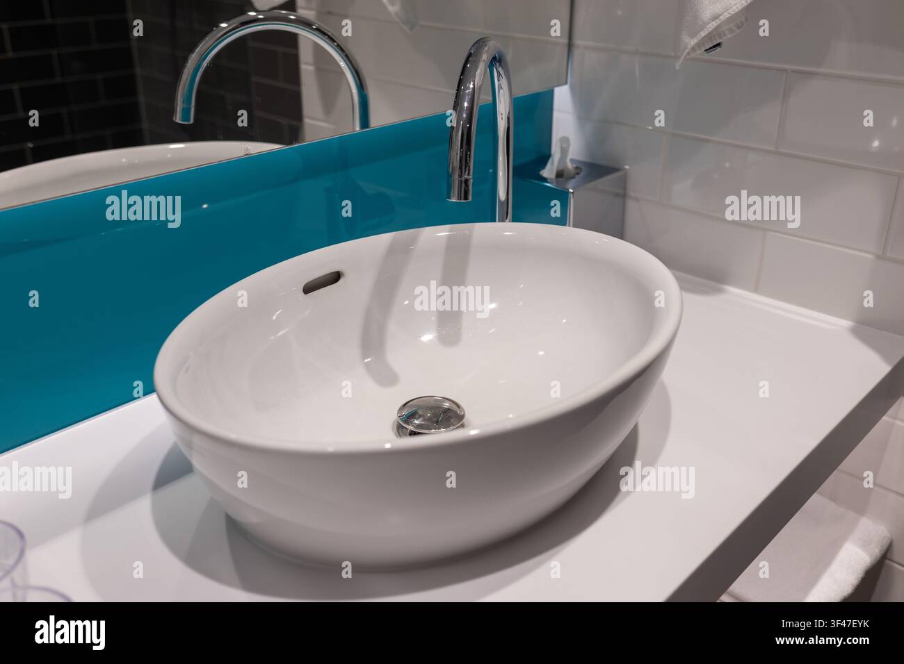 Saubere Handtücher, die an einem Waschbecken in einem modernen Badezimmer mit blauen Akzenten und einem Spiegel hängen Stockfoto