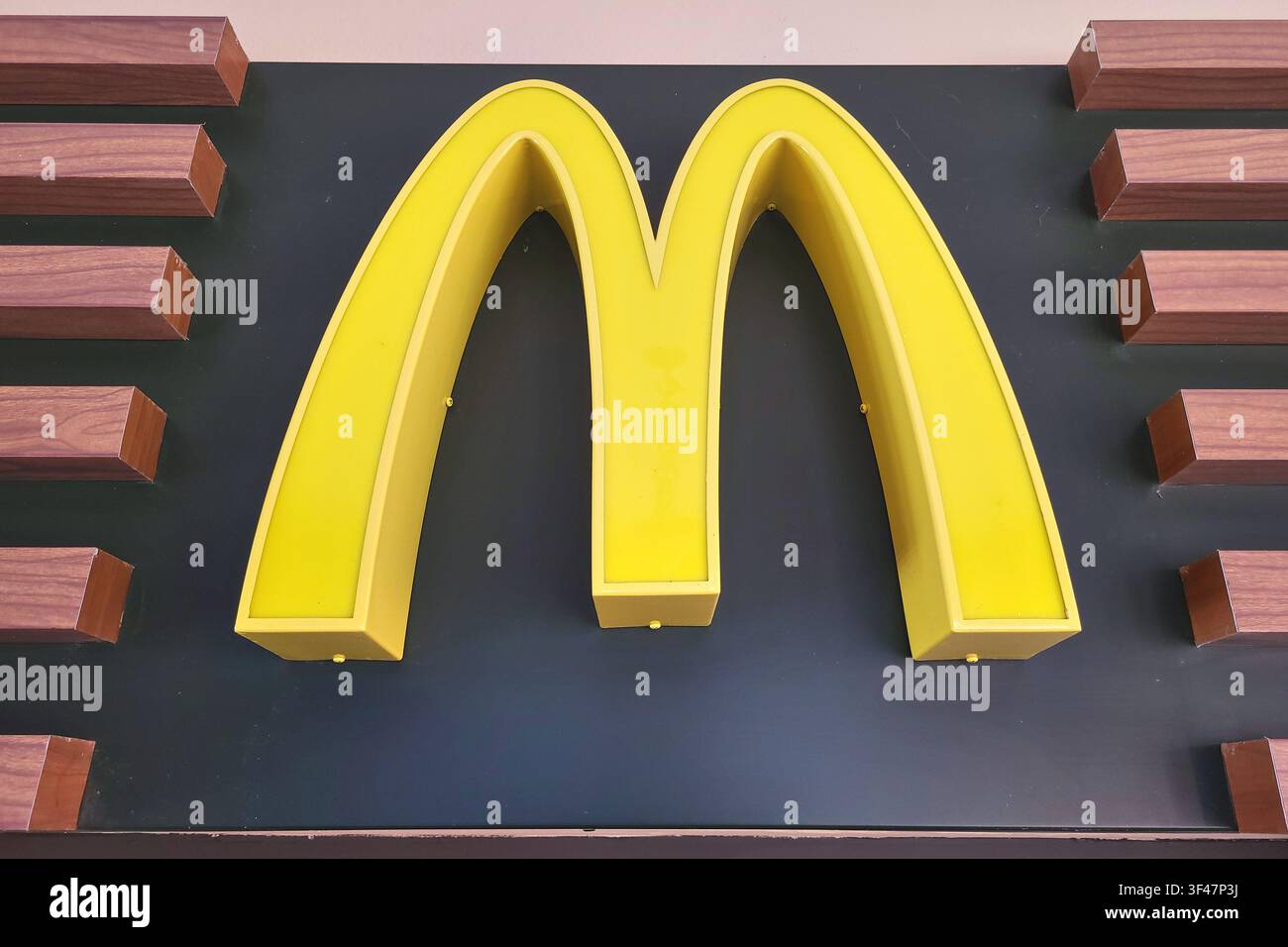 Nahaufnahme des ikonischen McDonald's Golden Arches-Logos auf einer modernen schwarz- und holzfarbenen Wandfassade. Stockfoto