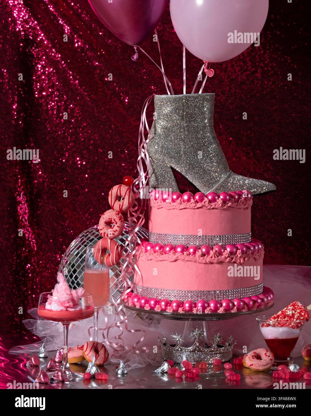 Rosa & silberne Disco-Party mit Strass-Stiefel, Discokugel, Cocktails, Eiscreme und rosa Kuchen, der mit Kaugummibällchen verziert ist. Heißrosa Paillettenhintergrund. Stockfoto