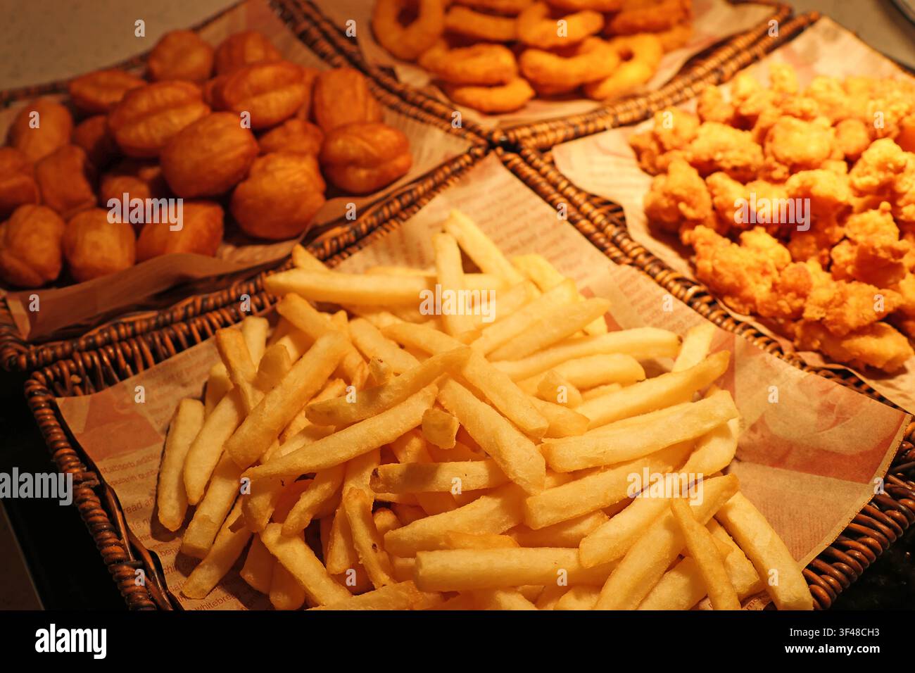 Verschiedene gebratene Snacks in Körben wie knusprige Pommes frites, Zwiebelringe, Hühnerschöpfer und Teig, serviert in einem Restaurant in Changsha City, Hunan Stockfoto