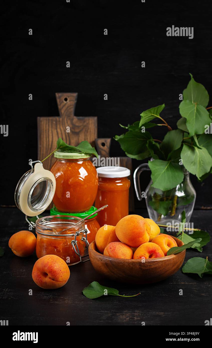 Frische Aprikosen und Aprikosenkonfitüre auf rustikalem dunklem Hintergrund Stockfoto