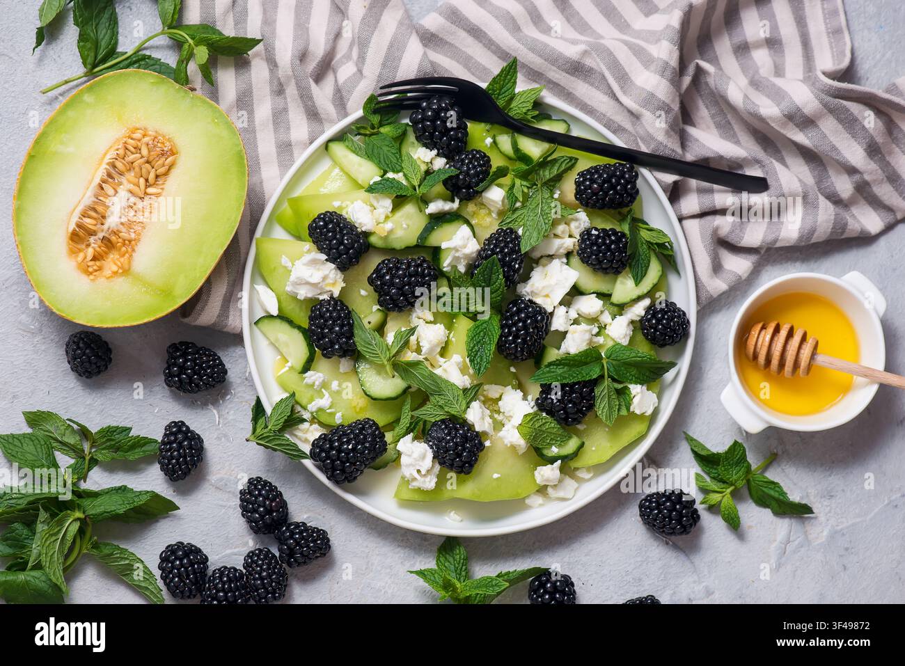 Salat mit Melone, Brombeeren, Gurken, Feta und Minze mit Honigdressing. auf einem weißen Teller. Top-Down-Ansicht.selektive Fokussierung Stockfoto