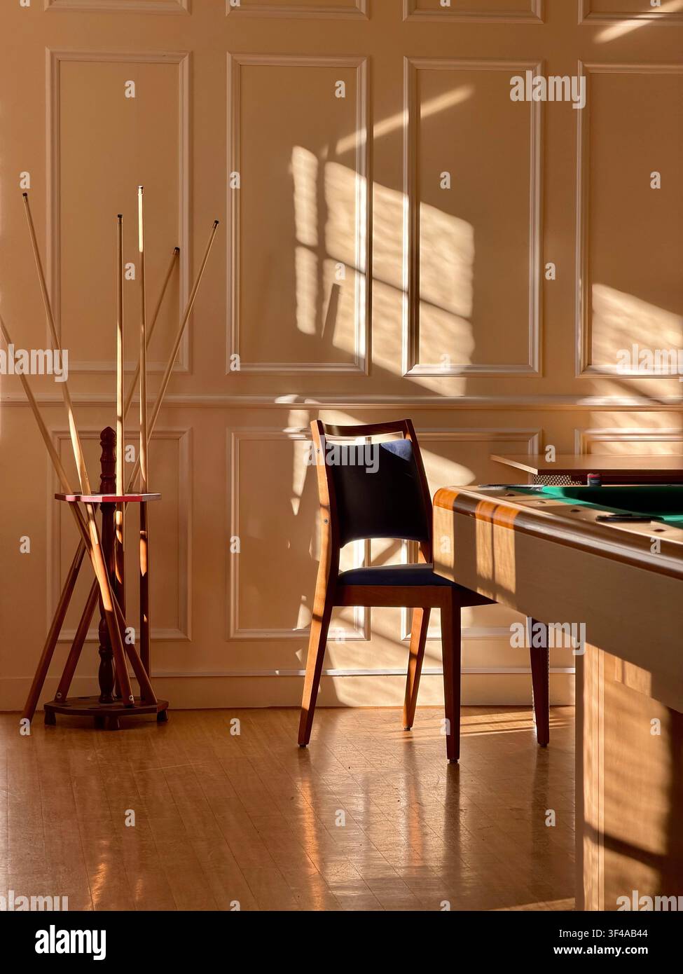 Antiker Kartentisch und Ledersessel in einem sonnendurchfluteten, holzvertäfelten Spielzimmer, Deutschland - Smartphone-aufgenommenes Stockfoto